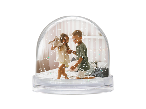 Schneekugel zeigt Jungen und Mädchen auf einem Bett; das Mädchen hält einen Kuschelhasen liebevoll in der Hand.