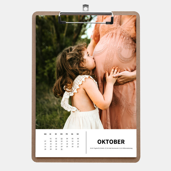 Der Klemmbrettkalender im A4-Hochformat zeigt ein Mädchen, das liebevoll den Babybauch ihrer schwangeren Mutter küsst.