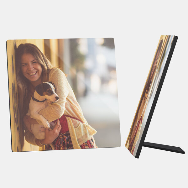 Ein quadratischer Fotoaufsteller zeigt ein fröhliches Bild von einer jungen Frau, die einen kleinen Hund im Arm hält. Die Frau hat lange, gewellte Haare und lacht, während sie den Hund liebevoll ansieht. 